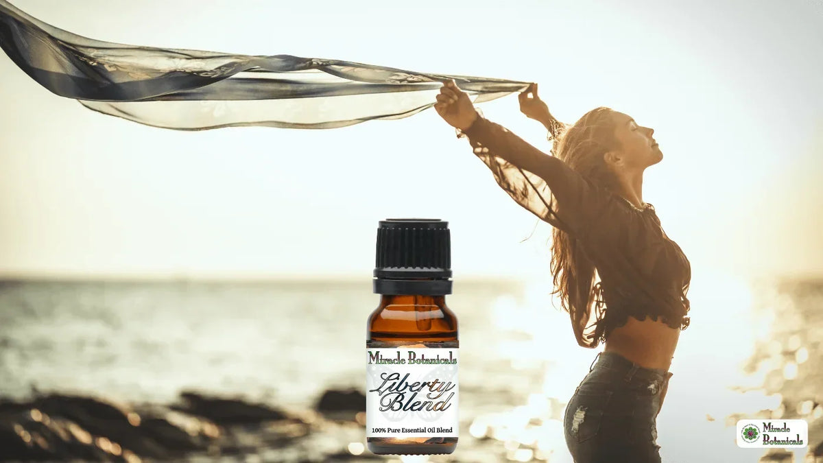 Liberty Blend essential oil bottle beside a woman holding a flowing scarf overhead on a sunlit beach