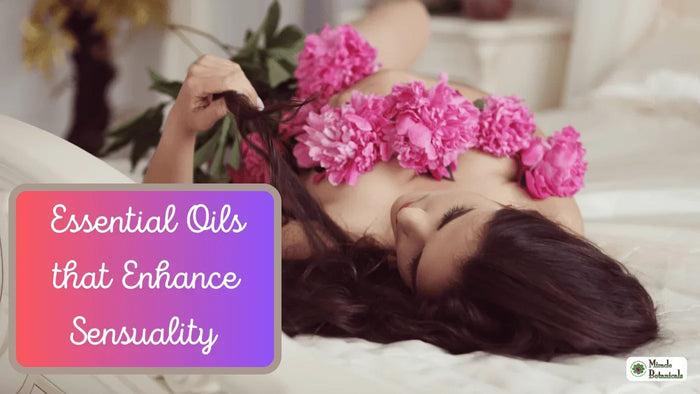 Woman with long dark hair lying on white sheets with pink peonies across her chest, with text: Essential Oils that Enhance Sensuality