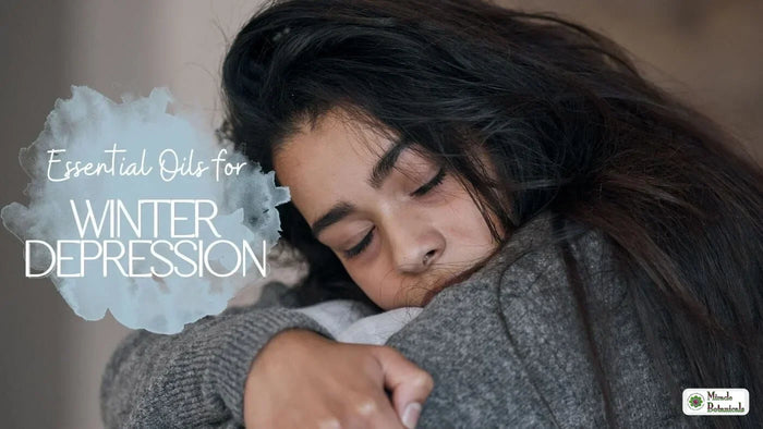 Woman resting her head on her arm in a grey sweater, with the title Essential Oils for Winter Depression