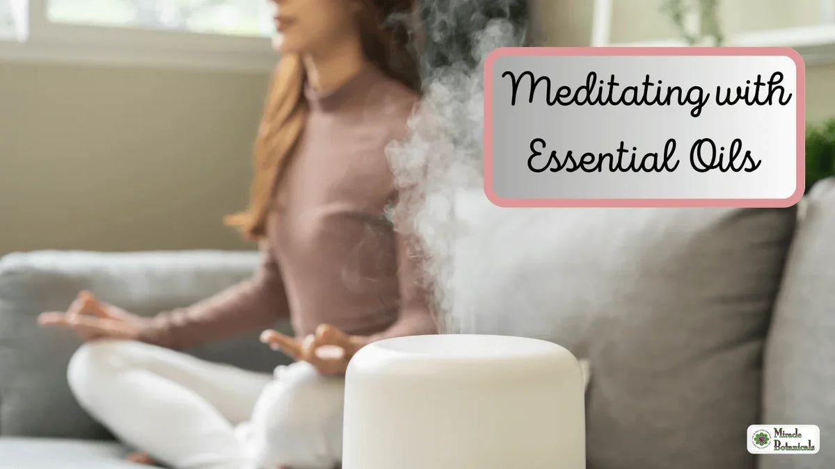 Woman meditating cross-legged on a sofa behind a white diffuser releasing mist, with text: Meditating with Essential Oils