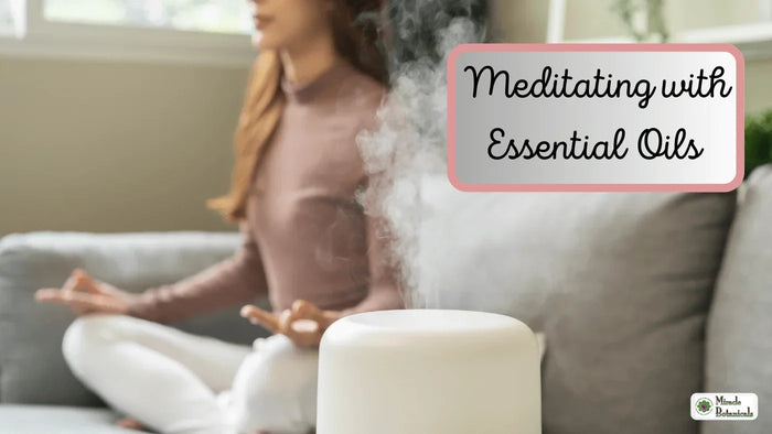 Woman meditating cross-legged on a sofa behind a white diffuser releasing mist, with text: Meditating with Essential Oils