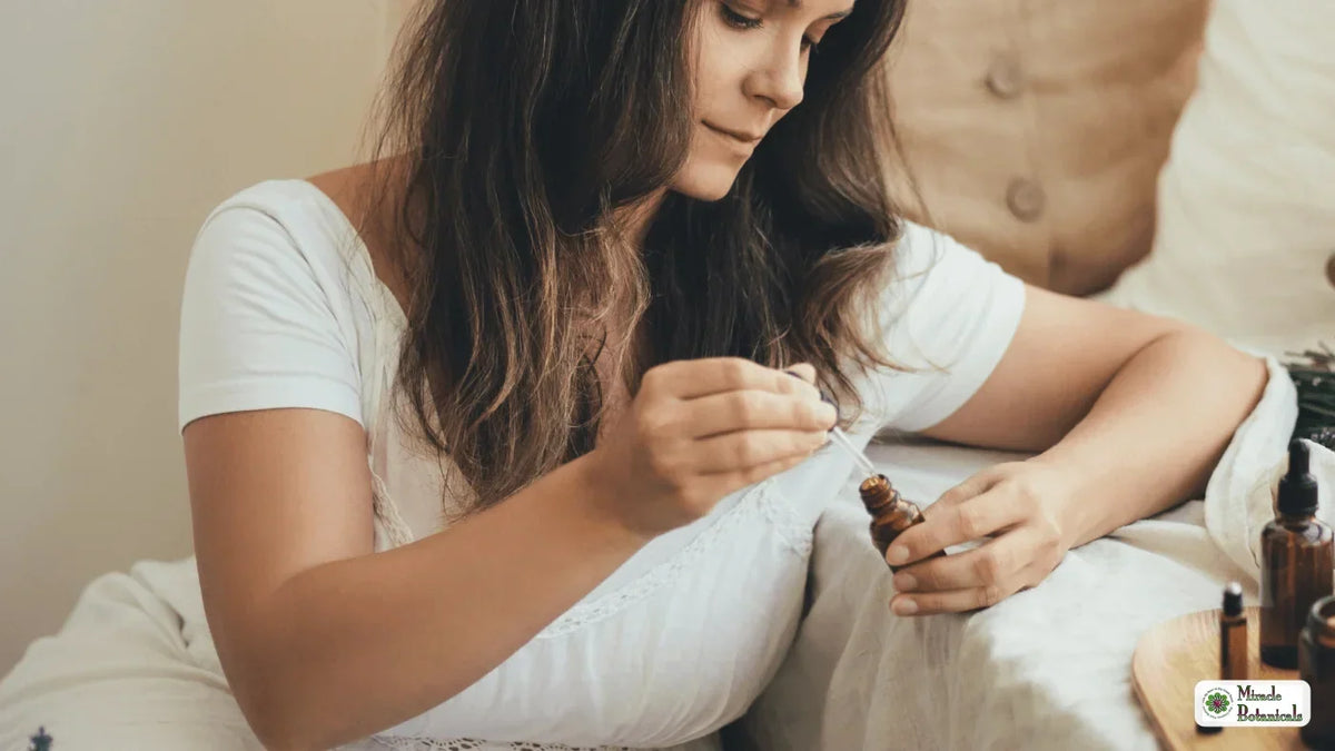 Woman in a white T-shirt filling a dropper from a small amber essential oil bottle on her bed