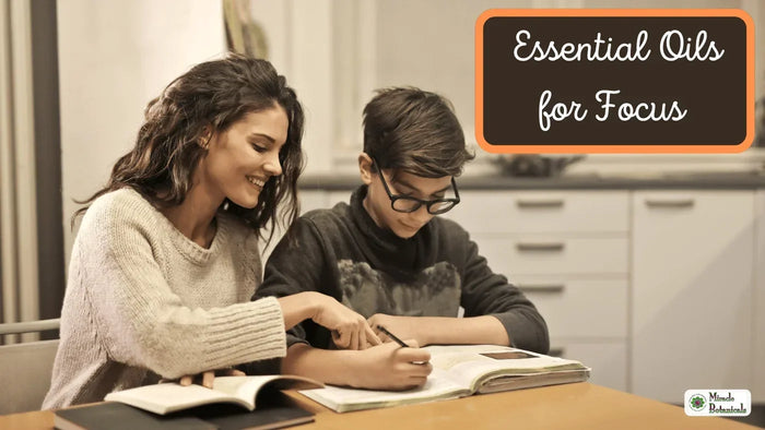 Smiling woman helping a boy in glasses with his writing at a table, with text: Essential Oils for Focus